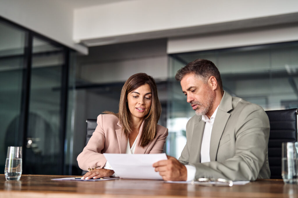 Two professional executives discussing financial accounting papers in office.