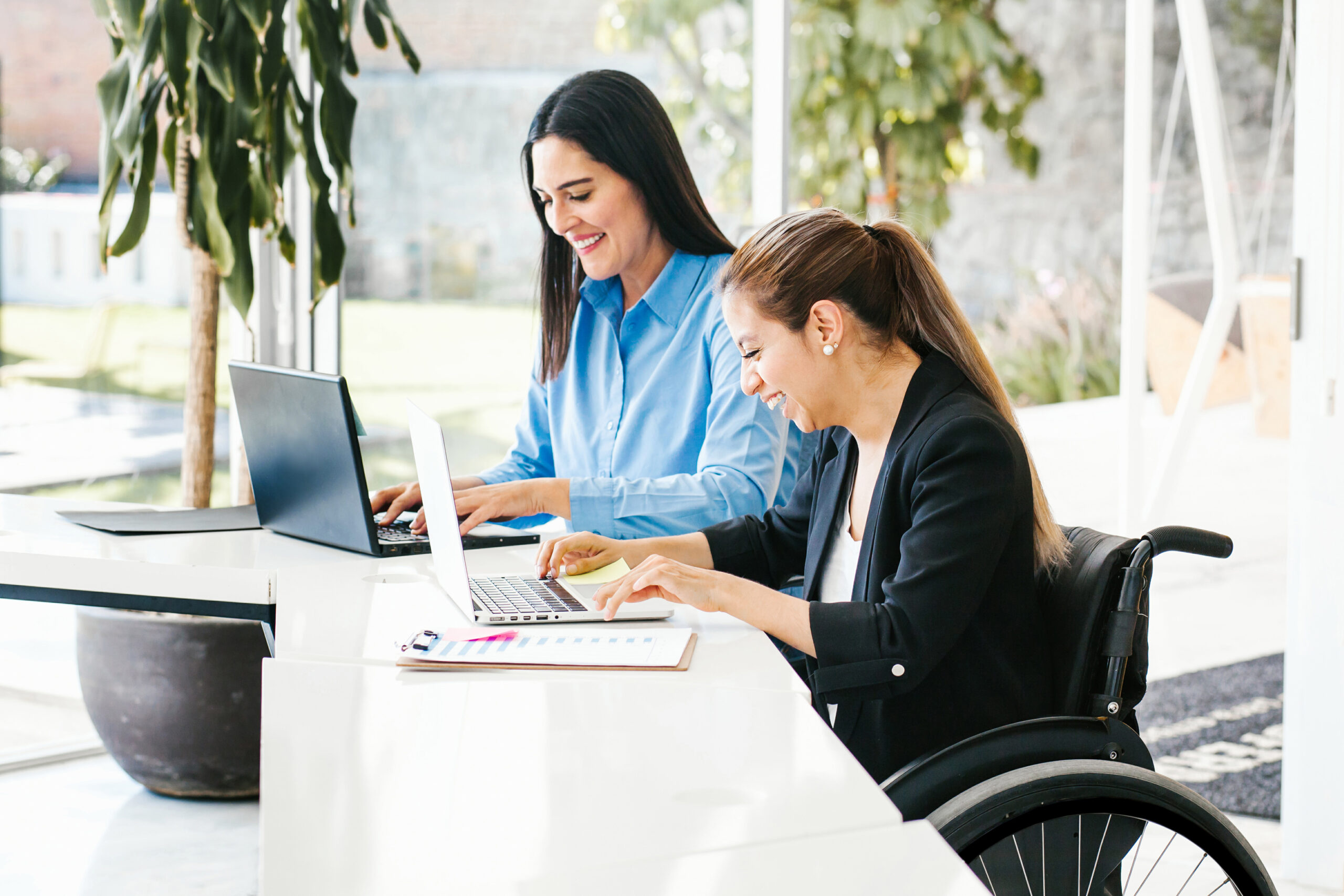 Women working in office one girl in wheelchair with computer