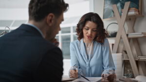 Businesswoman conducting job interview with elegant man at office desk closeup. Serious hr manager discussing work experience with male candidate. Confident woman ceo analyzing documents with partner.